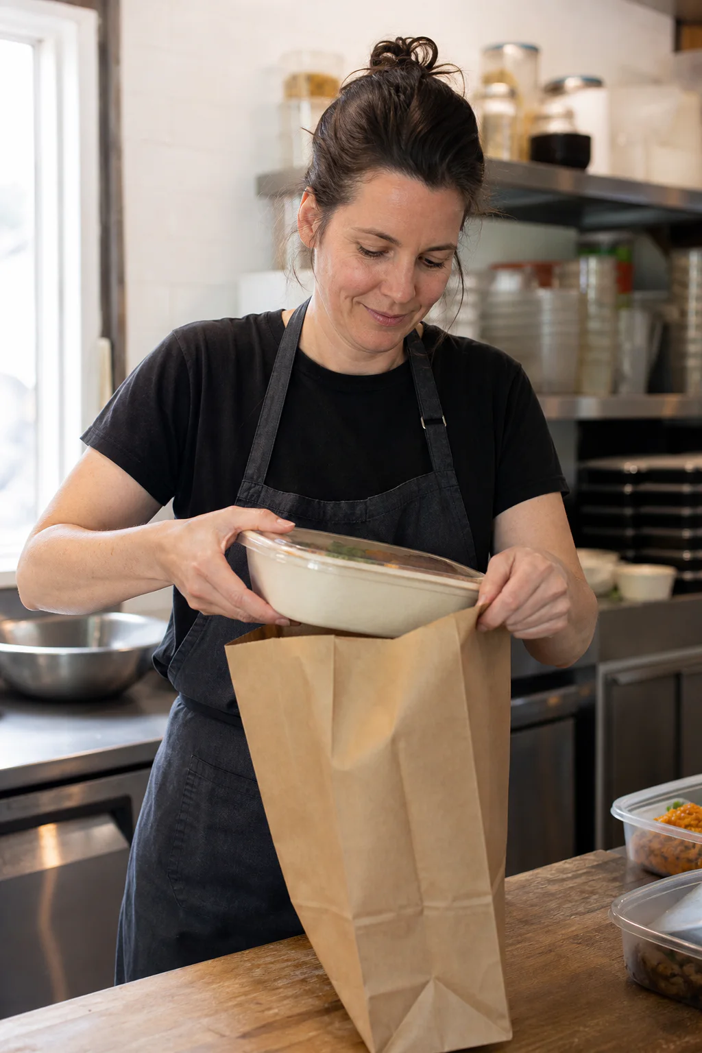 Une vendeuse francophone au Canada place un repas préparé dans un sac de ramassage en papier